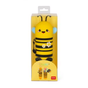 A full product shot of a cute, bee-shaped pencil case by Legami, shown in its clear plastic packaging, isolated on a white background. The pencil case is a vibrant yellow with black horizontal stripes and two white daisies with yellow centres. The top part of the case, which acts as the bee's head, has a smiling kawaii-style face. The colourful packaging features a yellow background with illustrations of the pencil case and the Legami logo at the bottom.