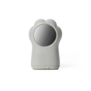 A back view of a grey pencil sharpener shaped like a cat's paw. It has a round mirror on the back where the paw pad would be.